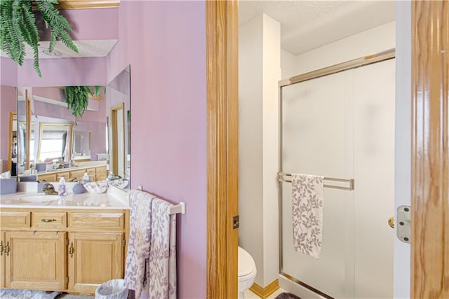 bathroom with vanity, a shower stall, and toilet