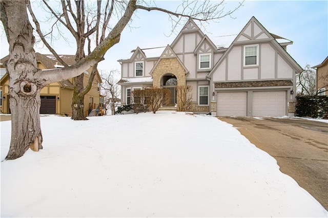 tudor-style house with stone siding, aphalt driveway, an attached garage, and stucco siding