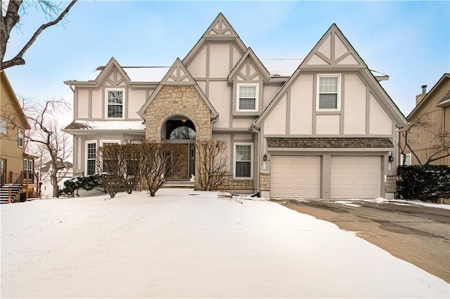 tudor home featuring aphalt driveway, stone siding, a garage, and stucco siding