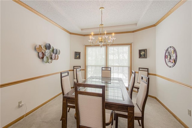 carpeted dining room featuring a tray ceiling, crown molding, a textured ceiling, a chandelier, and baseboards