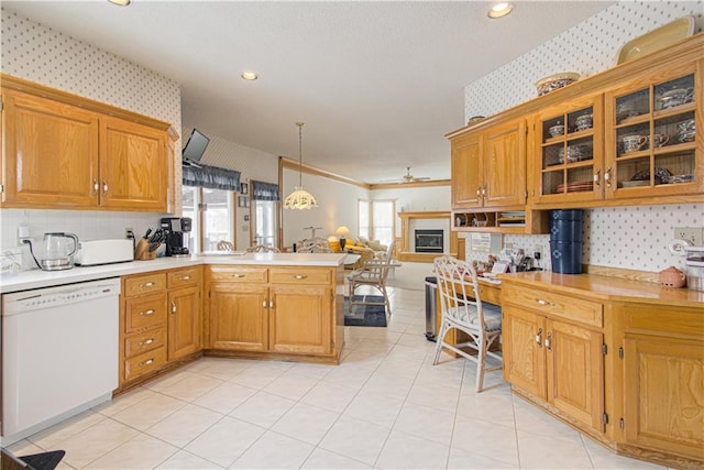 kitchen featuring a peninsula, white dishwasher, light countertops, and wallpapered walls