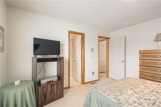 bedroom featuring a textured ceiling, baseboards, and light colored carpet