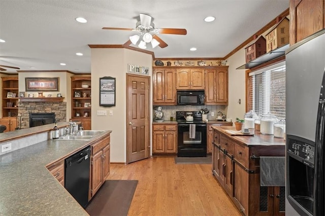 kitchen with a fireplace, sink, black appliances, crown molding, and light wood-type flooring