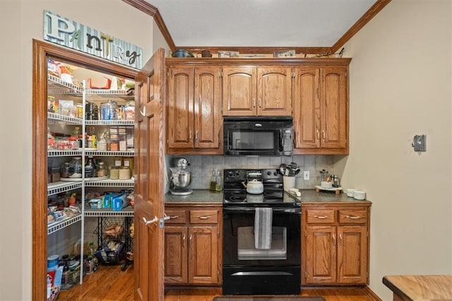 kitchen featuring tasteful backsplash, crown molding, black appliances, and light wood-type flooring