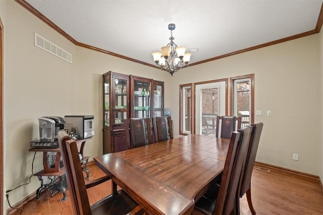 dining area with an inviting chandelier, crown molding, and light wood-type flooring