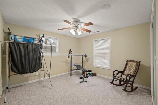 exercise room with ceiling fan, a textured ceiling, and carpet flooring