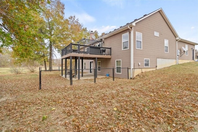 rear view of house with a wooden deck and a lawn