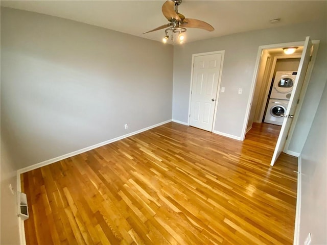 unfurnished bedroom featuring ceiling fan, stacked washer / dryer, and light hardwood / wood-style flooring