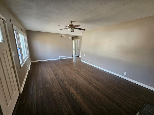 empty room featuring dark hardwood / wood-style flooring, ceiling fan, and a textured ceiling