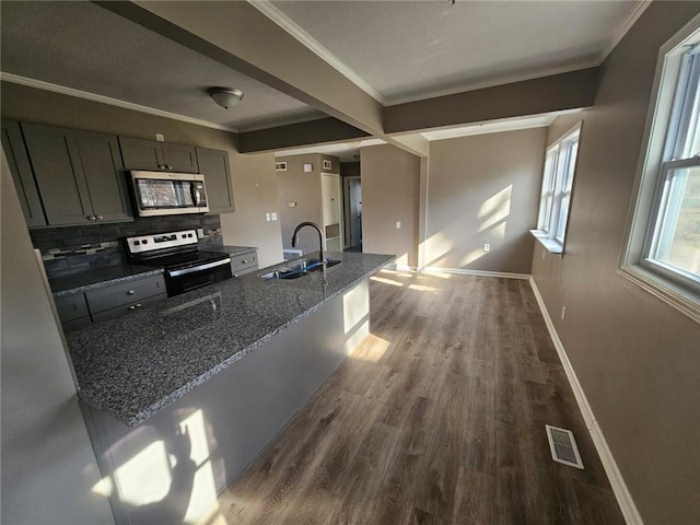 kitchen featuring sink, crown molding, dark stone counters, and appliances with stainless steel finishes