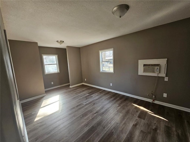 empty room featuring a wall unit AC, dark hardwood / wood-style floors, and a textured ceiling