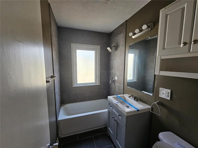 full bathroom with tiled shower / bath combo, vanity, toilet, tile patterned floors, and a textured ceiling