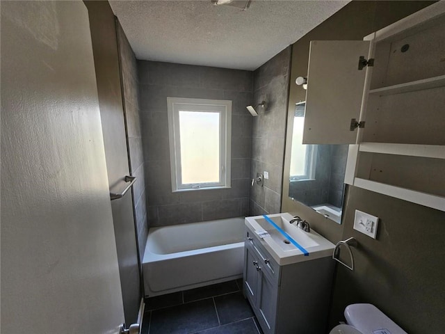 full bathroom featuring vanity, a textured ceiling, tiled shower / bath, tile patterned floors, and toilet