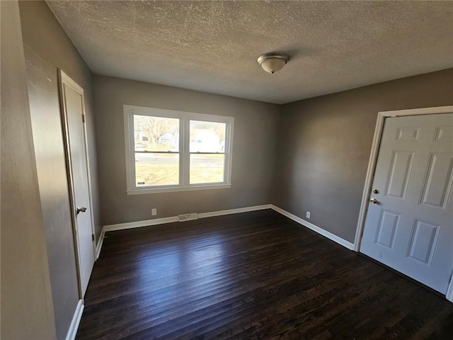 empty room with dark hardwood / wood-style flooring and a textured ceiling