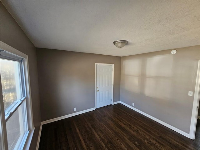 empty room with dark wood-type flooring and a textured ceiling