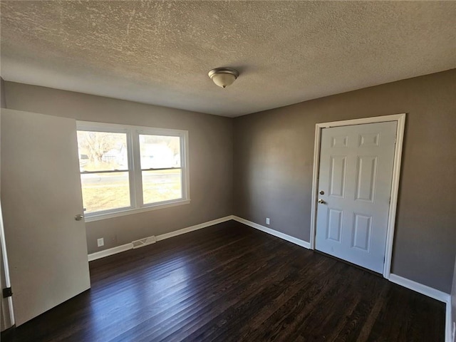 unfurnished room with dark wood-type flooring and a textured ceiling