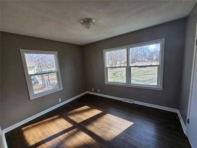 empty room featuring a textured ceiling and dark hardwood / wood-style flooring