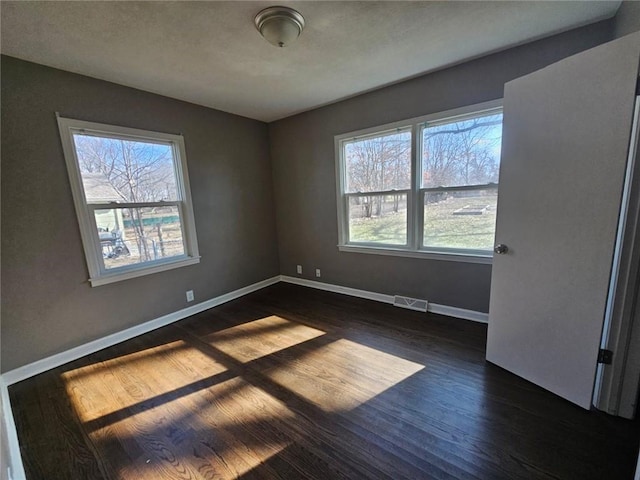 unfurnished room featuring dark hardwood / wood-style flooring and a wealth of natural light