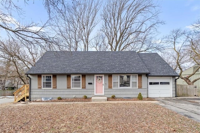 ranch-style house with a garage, roof with shingles, driveway, and fence