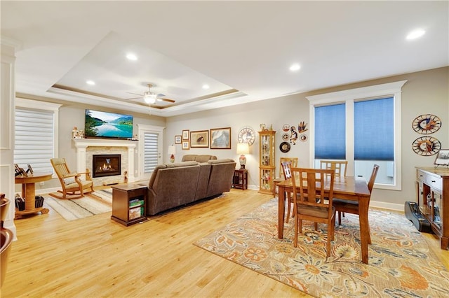 dining space featuring a raised ceiling, ceiling fan, and light hardwood / wood-style floors