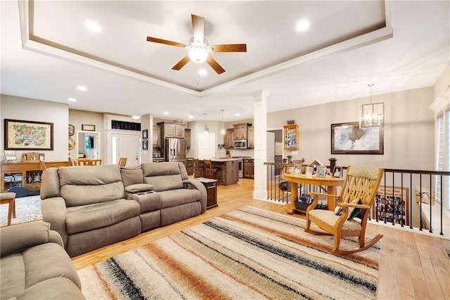 living room with crown molding, light hardwood / wood-style floors, and a raised ceiling