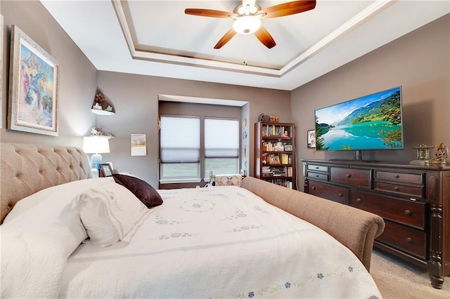 bedroom featuring a raised ceiling, light colored carpet, and ceiling fan