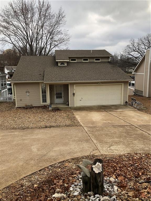 view of front of property with a garage, concrete driveway, and roof with shingles