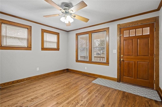 foyer entrance with ornamental molding, ceiling fan, and light wood-type flooring