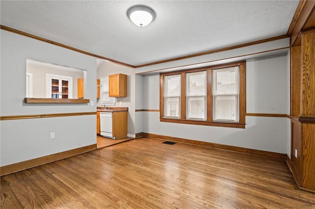 unfurnished living room with sink, ornamental molding, a textured ceiling, and light wood-type flooring