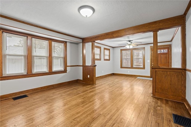 unfurnished living room with ceiling fan, ornamental molding, light hardwood / wood-style floors, and a textured ceiling