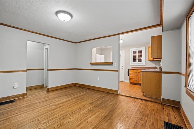 kitchen with crown molding, light hardwood / wood-style floors, a textured ceiling, and white refrigerator