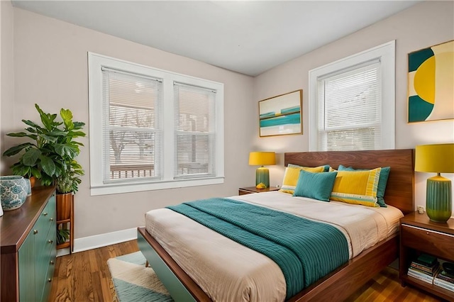 bedroom with dark hardwood / wood-style floors and multiple windows