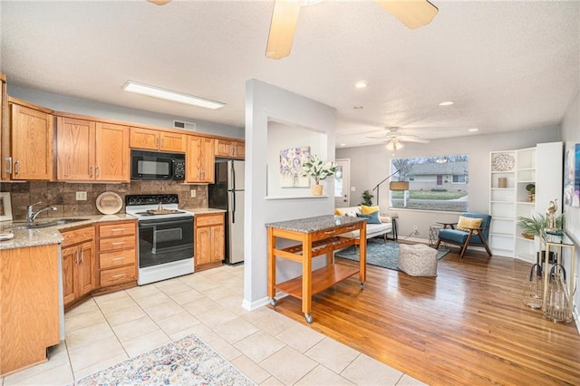 kitchen featuring white electric range, sink, stainless steel refrigerator, ceiling fan, and decorative backsplash