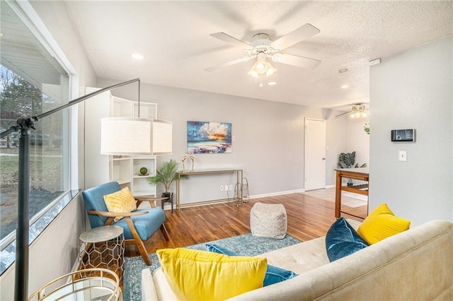 living room featuring ceiling fan, wood-type flooring, and a textured ceiling