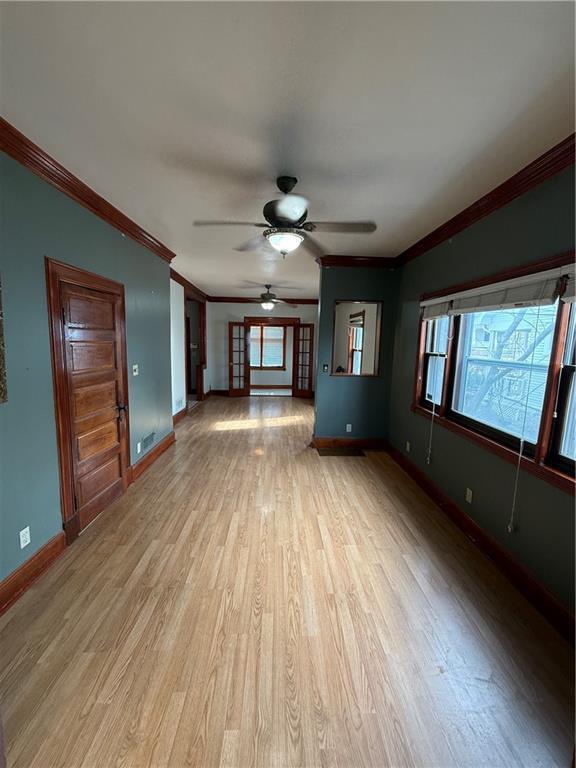 unfurnished living room featuring crown molding, ceiling fan, and light wood-type flooring