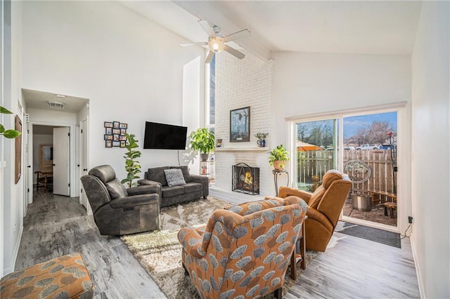 living room with ceiling fan, a brick fireplace, high vaulted ceiling, and light hardwood / wood-style flooring