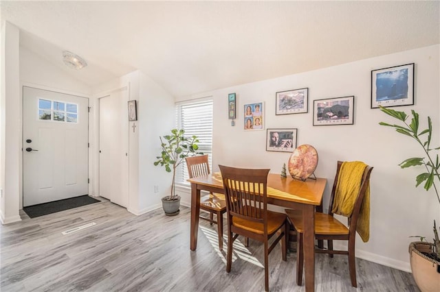 dining space with lofted ceiling and light wood-type flooring