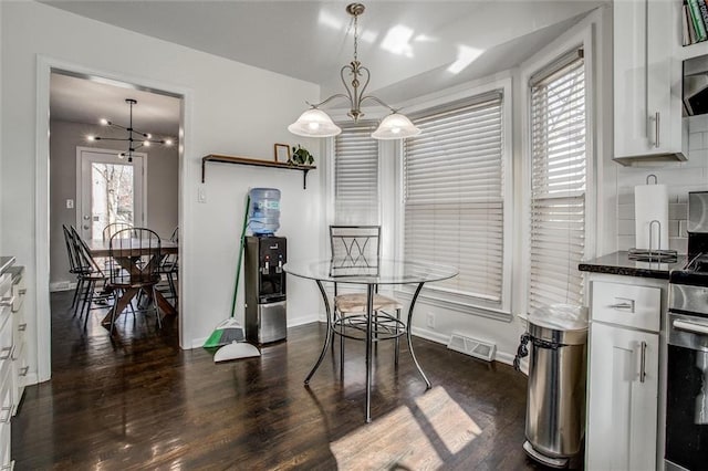 dining area with dark wood-style floors, visible vents, baseboards, and a notable chandelier