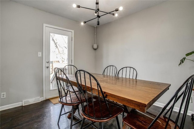 dining space with a notable chandelier, wood finished floors, visible vents, and baseboards