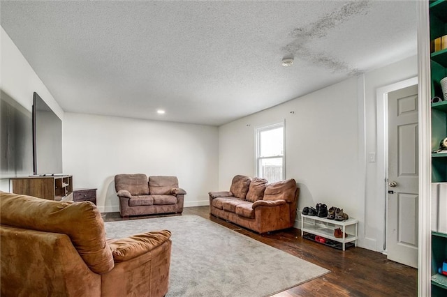 living area with baseboards, a textured ceiling, and dark wood finished floors