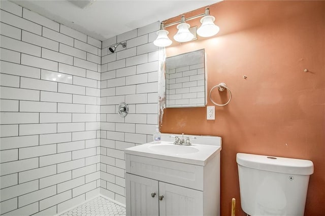 bathroom with toilet, vanity, and a tile shower