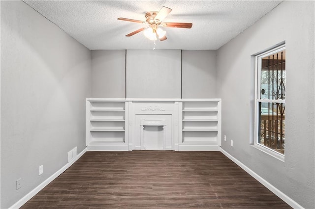 unfurnished living room with ceiling fan, dark hardwood / wood-style flooring, a textured ceiling, and a fireplace