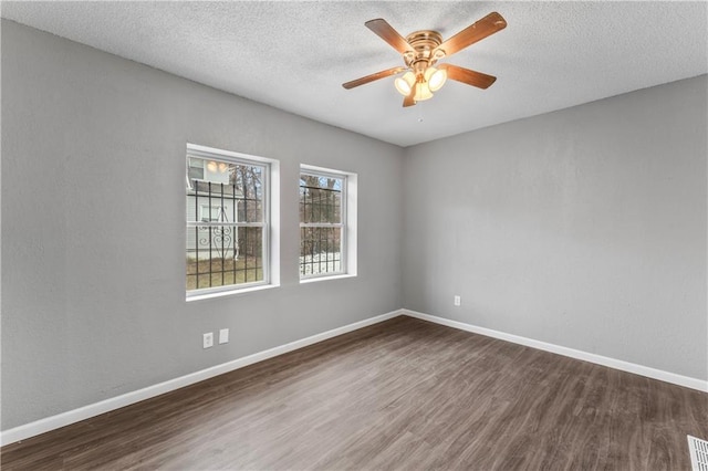 unfurnished room with ceiling fan, a textured ceiling, and dark hardwood / wood-style flooring