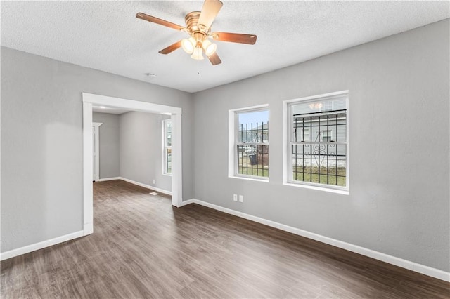 empty room featuring ceiling fan, dark wood-type flooring, and a textured ceiling