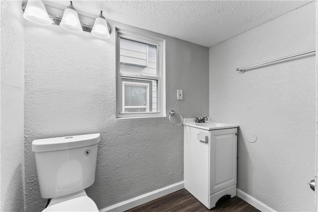 bathroom featuring vanity, hardwood / wood-style floors, a textured ceiling, and toilet