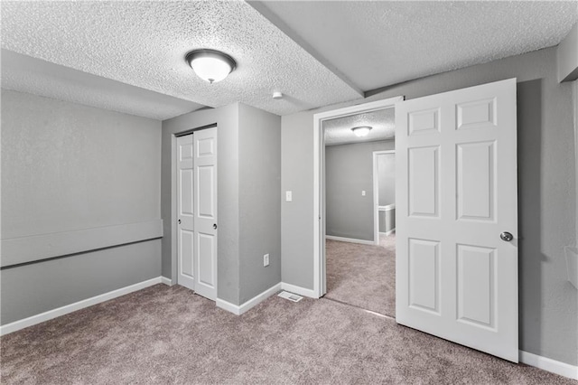 unfurnished bedroom featuring light carpet, a textured ceiling, and a closet