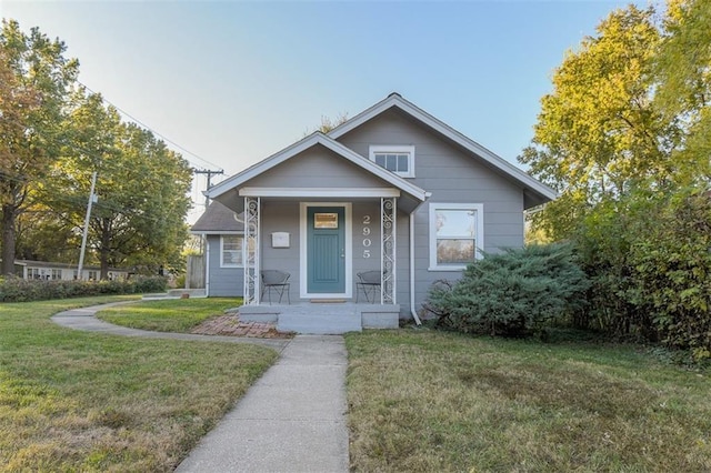 bungalow featuring covered porch and a front yard