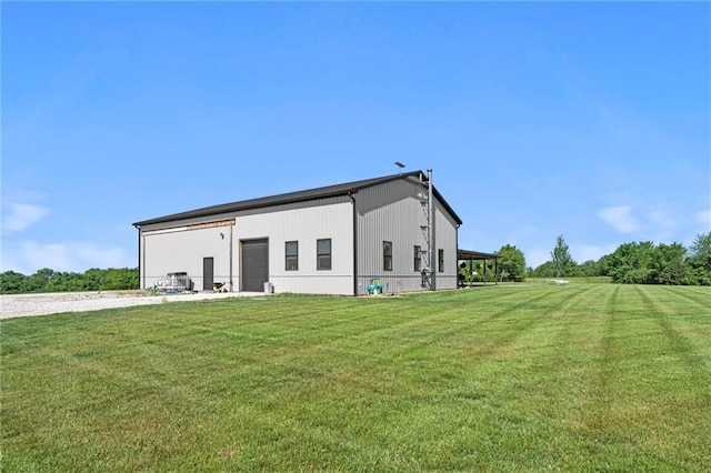16140 214th St, Tonganoxie, KS 66086 - back of house featuring a detached garage, a lawn, and an outbuilding