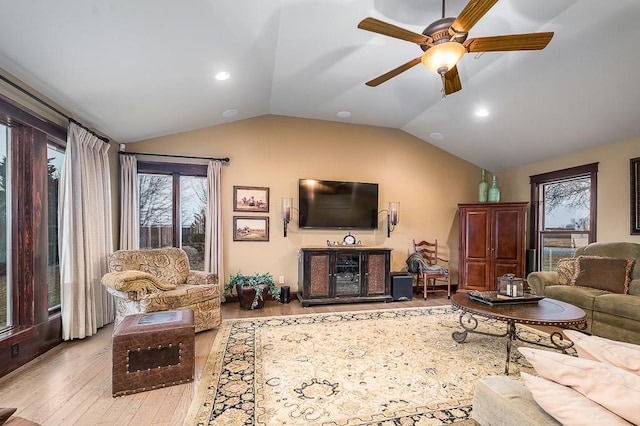 living area with ceiling fan, plenty of natural light, wood finished floors, and vaulted ceiling