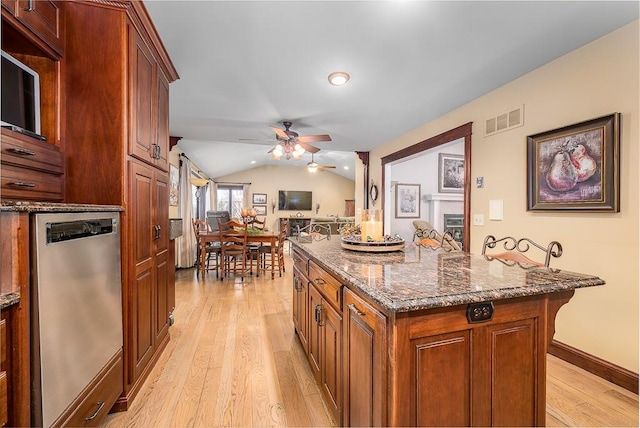 kitchen with visible vents, dishwasher, lofted ceiling, light wood-style flooring, and dark stone countertops